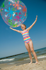 Wall Mural - Little girl playing ball at the beach