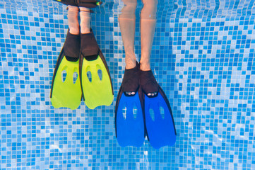 Underwater kid's legs in fins in swimming pool