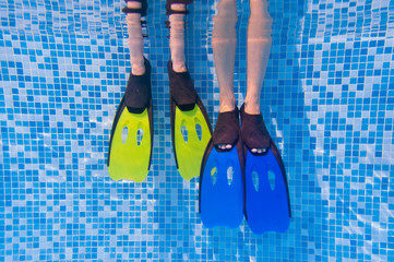 Underwater kid's legs in fins in swimming pool