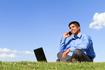 businessman with cell phone and laptop at the park