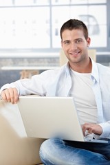 Sticker - Handsome man with laptop smiling on sofa