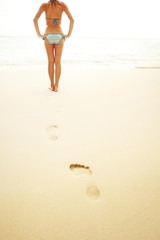 Canvas Print - Young woman standing on wet perfect sand and going to swim in a sea