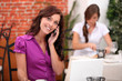 © auremar - Young woman on cellphone in a restaurant