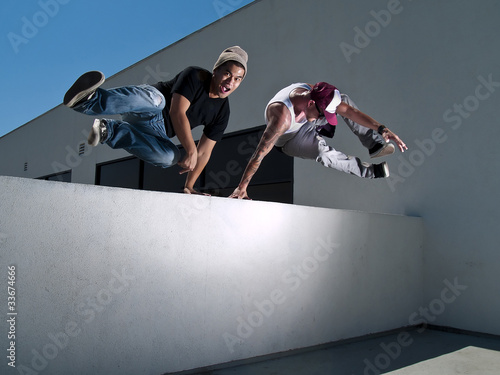 Plakat na papierze fotorealistycznym Dwóch mężczyzn parkour free biegaczy skaczących przez mur