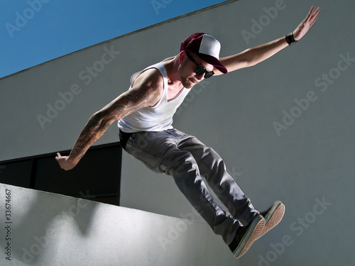 Plakat na papierze fotorealistycznym Wytatuowany mężczyzna parkour bezpłatny biegacz skaczący z budynku