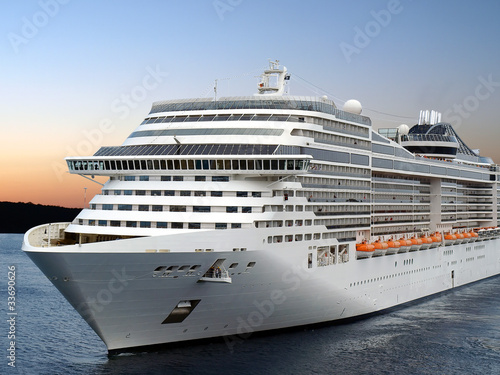 Fototapeta na wymiar Luxury cruise ship sailing from port on sunrise.