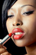 Beautiful african woman applying lipstick