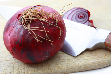 Fresh red onion with knife on choppig board