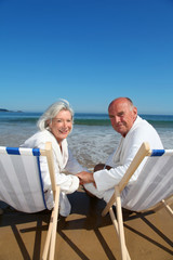 Wall Mural - Portrait of senior couple sitting in deckchairs