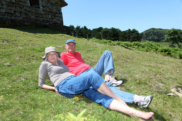 Wall Mural - Senior couple resting in meadow on a sunny day