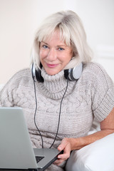 Wall Mural - Senior woman listening to music with headphones