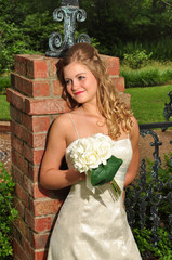 Caucasian bride leaning against a brick colume