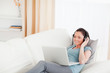 © WavebreakmediaMicro - Beautiful female with headphones relaxing on her laptop while ly