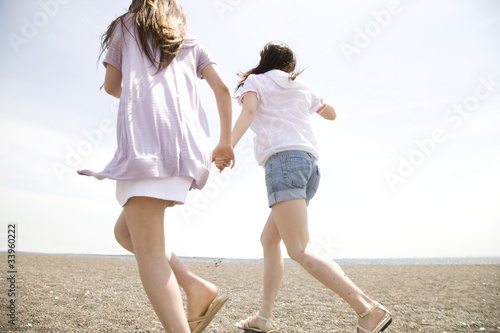 砂浜を走る2人の女性の後ろ姿 Stock Photo Adobe Stock