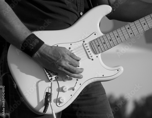 Fotoboard na płycie Człowiek grający na gitarze elektrycznej z bliska w czerni i bieli