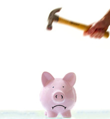 frowning piggy bank about to be smashed by a hammer