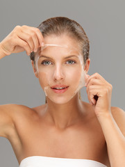 young woman taking off peeling mask