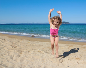 happy little girl jumping on the beach