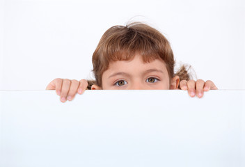 little girl hiding behind a board