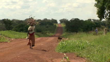 woman walking down dirt road in rural africa