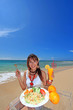 浜辺で昼食を取る笑顔の女性