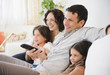 © JGI/Jamie Grill/Blend Images - Happy family sitting on sofa watching television