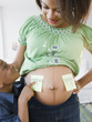 © JGI/Jamie Grill/Blend Images - Black boy pointing to adhesive notes on pregnant mother's stomach