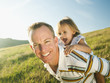 © Erik Isakson/Blend Images - Father carrying daughter on his back in field