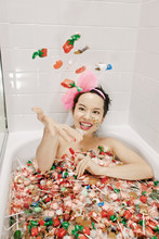 Mixed Race Woman Taking A Bath In Candy