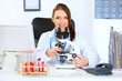 © Alliance - Smiling doctor woman using microscope in laboratory