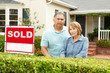 © Monkey Business - Senior Hispanic couple outside house with sold sign