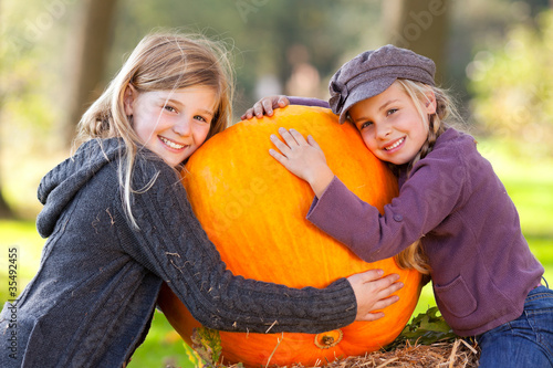 Vászonkép  two girls proud of their big pumpkin