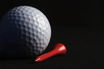 Golf ball with red tee on black background