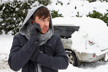 Young Man In Snow With Broken Down Car