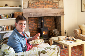 Young man eating meal by fire