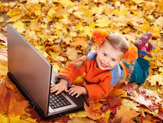 Wall Mural - child in autumn orange leaves with laptop.