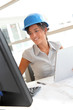 © goodluz - Smiling woman architect in office working on desktop computer