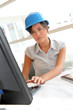 © goodluz - Smiling woman architect in office working on desktop computer