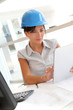 © goodluz - Smiling woman architect in office working with electronic tablet