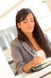 © goodluz - Portrait of beautiful businesswoman writing notes on agenda