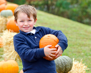 happy young boy picking a pumpkin for halloween
