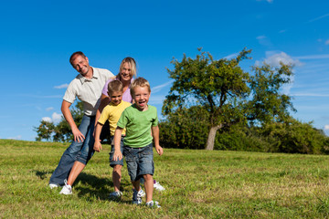 Familie mit Kindern spielt auf einer Wiese