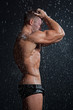 Muscle wet sexy young naked man posing under the rain in studio