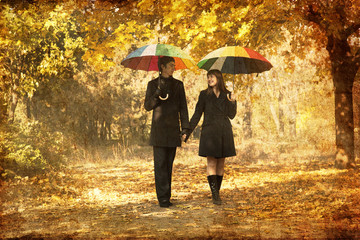 Couple walking at alley in autumn park.