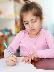 Schoolgirl works on her homework, writes on paper