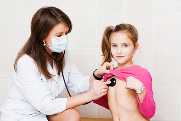 Female doctor examining child with stethoscope at clinic