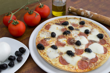 pizza with black olives and raw ingredients