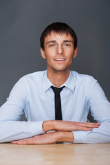 Portrait of young business man on a desk. He is sitting at his n