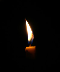 Closeup of burning candle isolated on black background.