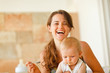 © Alliance - Portrait of laughing young mother feeding baby